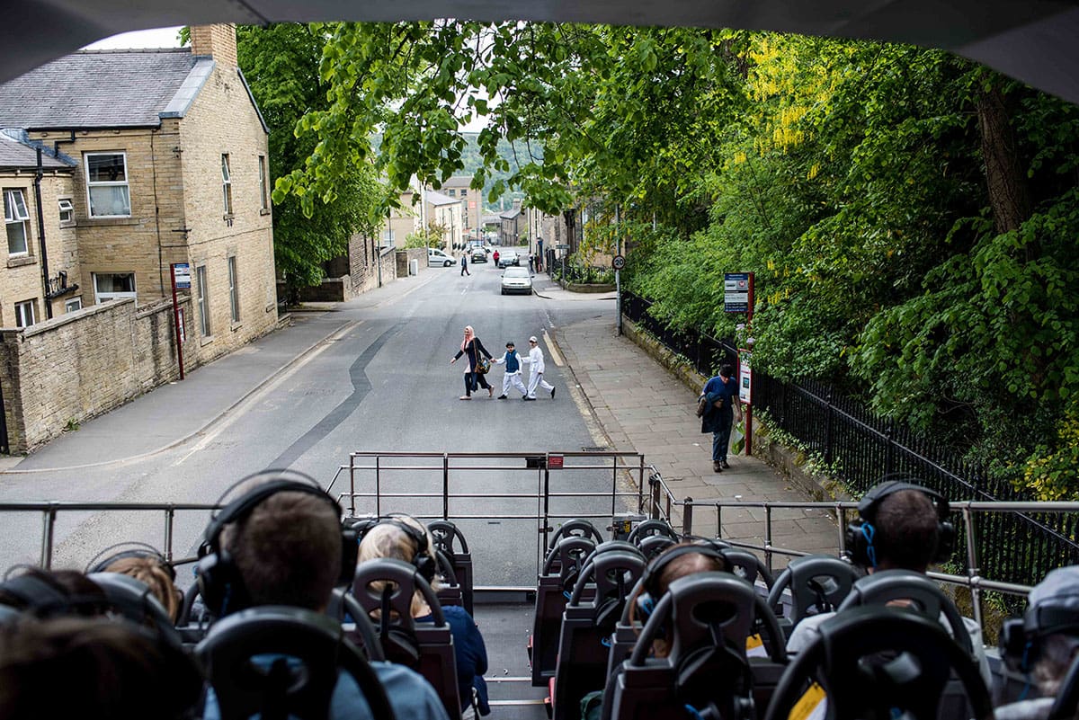 Photograph from the back of The Storytelling Bus looking back to a woman and two children crossing the road