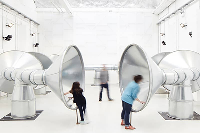 Photograph of two people peering into Speaking Tubes at IOU studio.