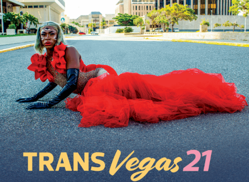 A person lies sideways on the floor. They have a red dress on, and black gloves. Underneath the image are the words Trans Vegas 21