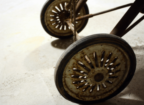 Two rusty old wheels sit infront of a white background.