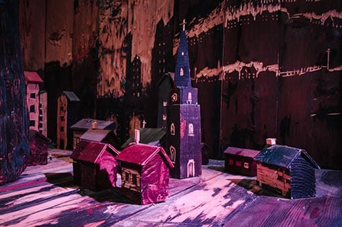 A carved 3D wooden model village featuring a church and several houses