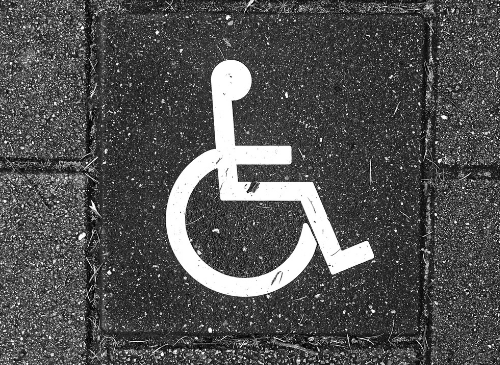 A white outlined drawing of a wheelchair is on a dark tiled floor.