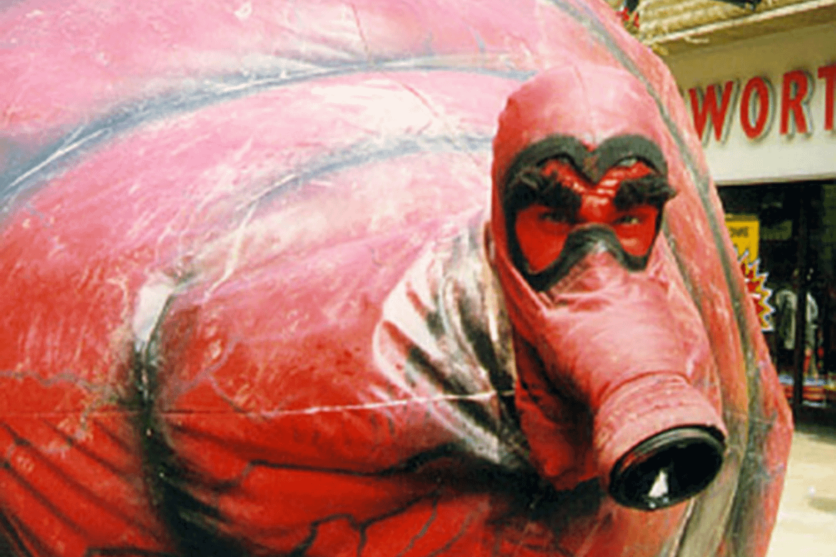 A large red rubber shape is close up to the camera. The shape has a face with thick black eyebrows.