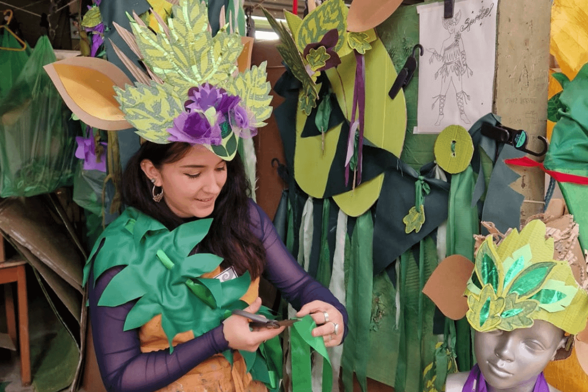 A woman sits among paper cut into the shapes of leaves.