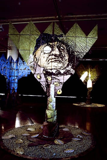 Large installation, picturing a backlit collage, the image is an old man wearing a monocle.