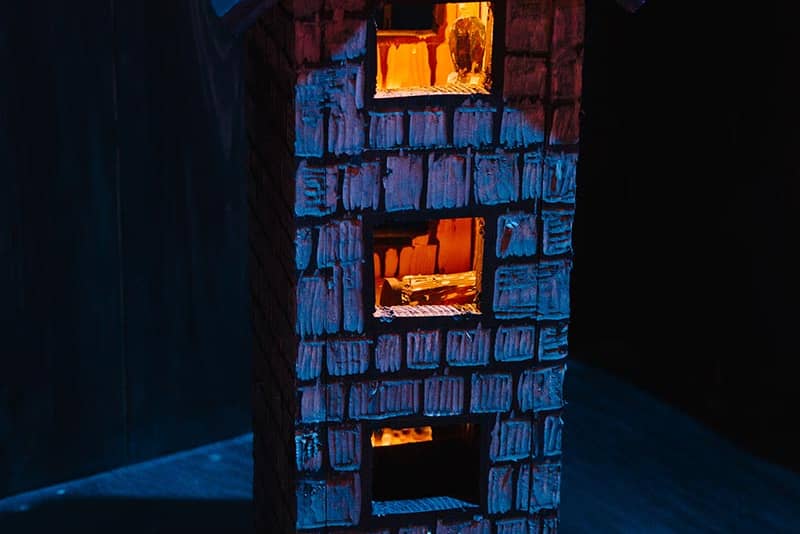 A model wooden house, with lights on in the windows