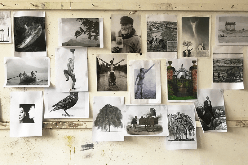 Montage of black and white photographs stuck to a wall.