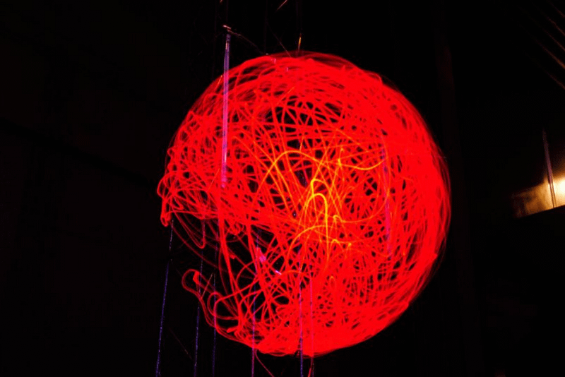 There is a large orange sphere with a dark background, the sphere is made of light rays.
